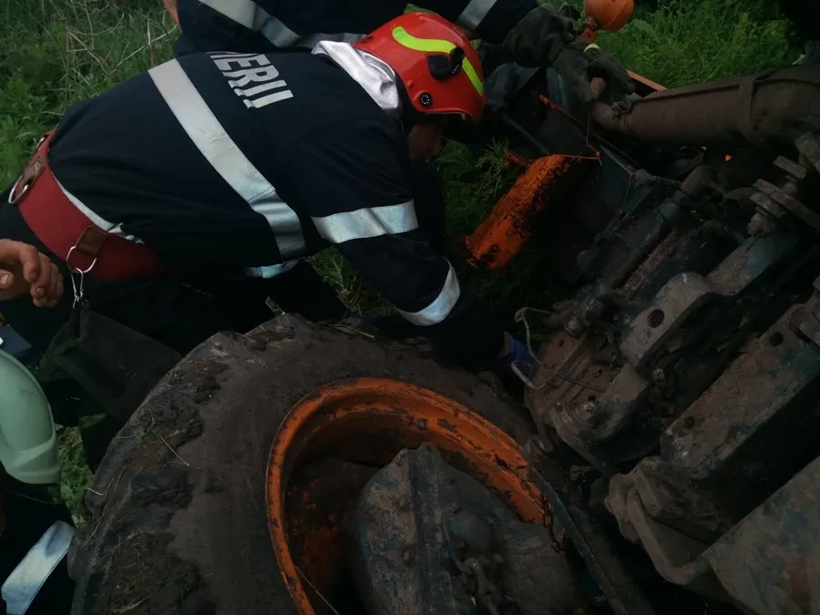 Pompieri chemați pentru a scoate un bărbat de sub un tractor răsturnat